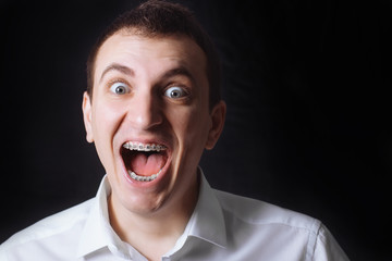 Portrait of a man of Caucasian appearance in orthodontic braces, metal brackets on his teeth in a...