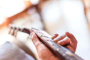 Young asian man playing spanish guitar indoors.