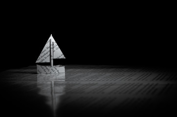 paper ship sailing on a paper sea with a black background - sea of words