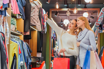 Young girls buying a lot of things in the store keep shopping bags.