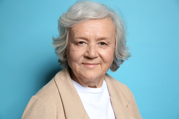 Portrait of elderly woman on color background