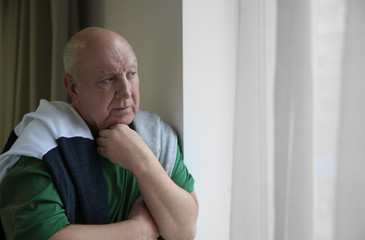 Fototapeta premium Portrait of elderly man near window indoors. Space for text
