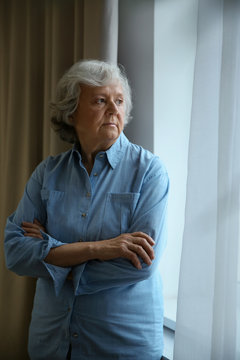 Portrait of elderly woman near window indoors