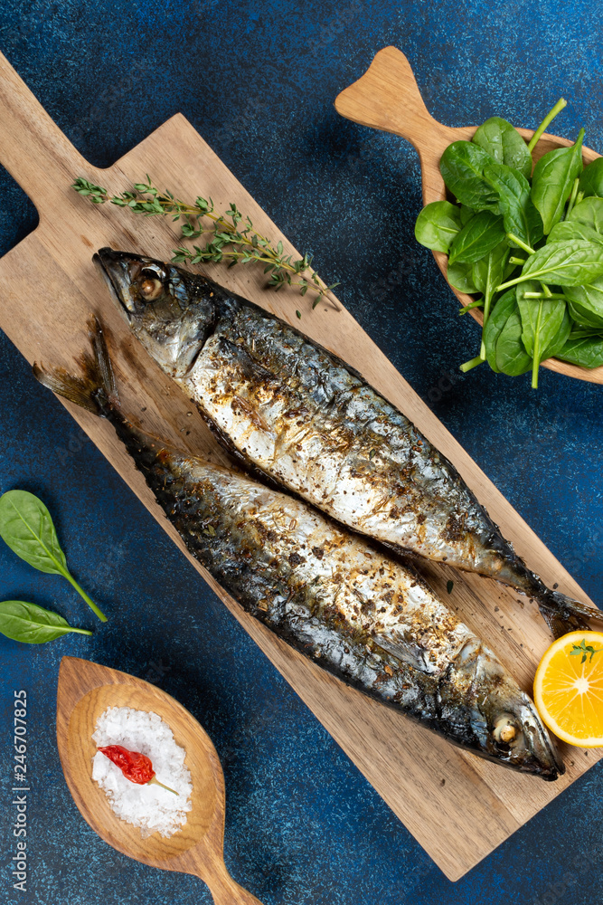 Wall mural baked mackerel fish on blue background, top view