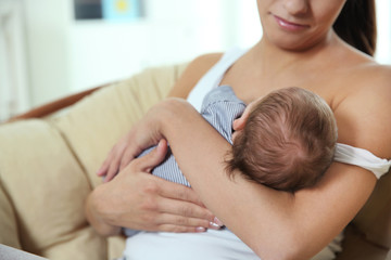 Obraz na płótnie Canvas Young woman breastfeeding her baby at home, closeup