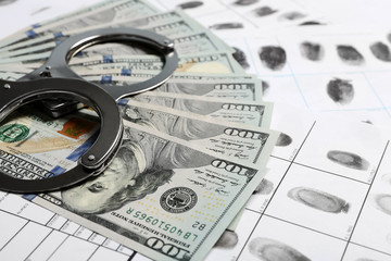 Handcuffs and cash on fingerprint cards, closeup