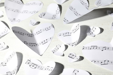 Paper hearts with music notes on white wooden background