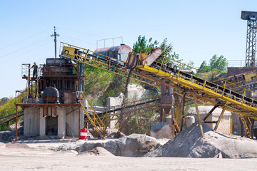 Crushing machinery, cone type rock crusher, conveying crushed granite gravel stone in a quarry open...