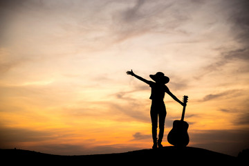 Silhouette woman with guitar At sunset