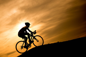 Naklejka na ściany i meble Silhouette cyclist at sunset.