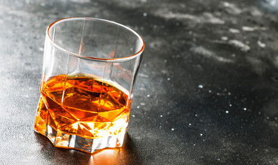 One glass of golden scotch whiskey on dark old bar table background, selective focus