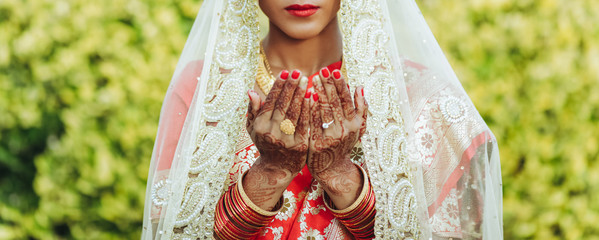 Hindu bride in white veil raises her hands up