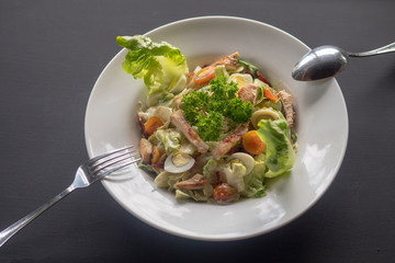 Caesar salad on a white plate on a dark background.