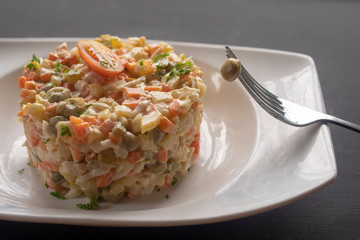 olivier salad on a white plate on a dark background