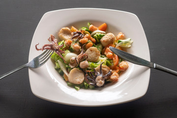 Seafood salad on a white plate on a dark background