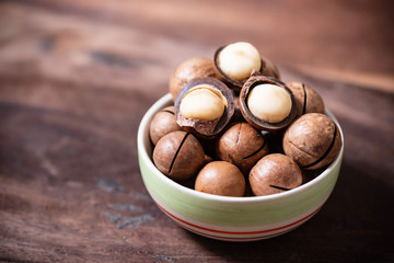 Macadamia nuts in a bowl on wooden background