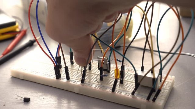 Maker, student or electronics engineer developing prototype electronics circuit on breadboard