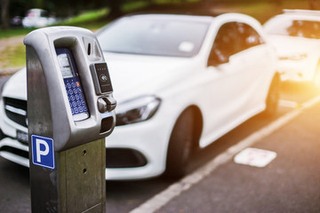 Parking machine or Parking meters with electronic payment in the city streets and a row of cars in...