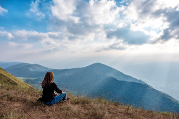 Fototapeta premium A woman sitting and watching sunset with mountains view in the evening