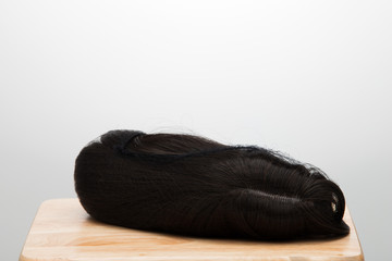 Artificial Fake Hair Wig on Rattan Head Mannequin wooden stand, studio lighting isolated on white gray close up detail of hair copy space text logo, color black curl straight top