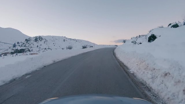 Driving on a snowy mountain road. Returning from Ziria ski center. Sunset colors in the horizon.