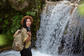 Fototapeta na wymiar Female hikers take pictures of themselves with beautiful waterfalls. Relax after hiking