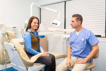 Obraz premium dentist talking to patient, stomatology and health care concept
