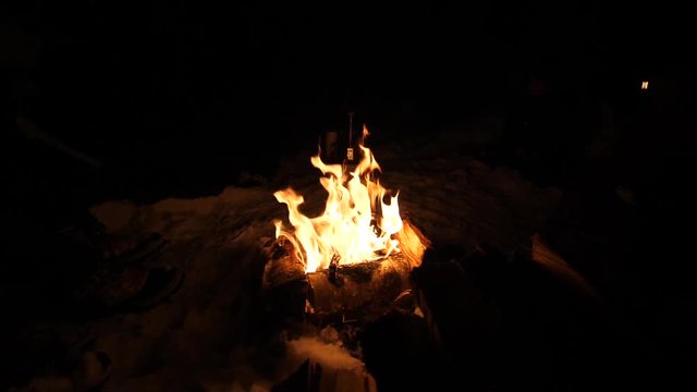 Slow motion firecamp bonfire outdoors at the frozen forest, with snowy icy ice in Dark night scene