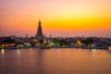 Obraz premium Wat Arun Temple Beside Chao Phraya River at Twilight Time in Bangkok, Thailand. One of the Most Famous Place of Thailand's Landmarks. Beautiful Sunset Sky with Smooth Water.