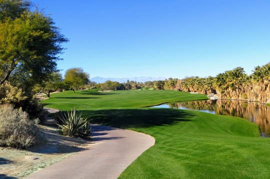 A beautiful view of a par 5 with the  desert surrounding the hole as well as a pond.  The golf course is in Palm Springs, California, United States.  A golf oasis.