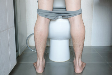 Rear view Leg of man standing peeing to toilet bowl in restroom at home  . Health concept