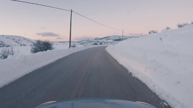 Driving on a snowy mountain road. Returning from Ziria ski center. Sunset colors in the horizon.