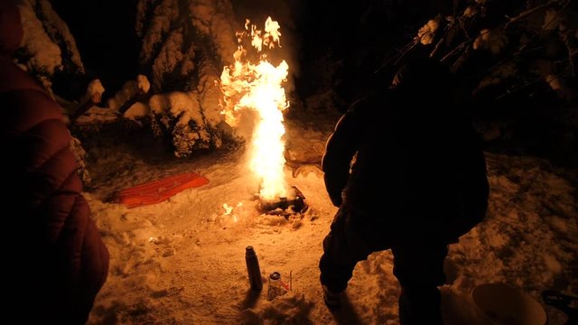 men lightning with torches firecamp Slow motion bonfire outdoors at the frozen forest with covered trees after heavy snow. slowmotion glowing flames