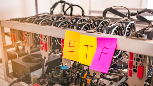 Digital Money Mining machine have pink and yellow note paper write the text "ETF" Stick on the rack. Concept Entering the Digital Money Fund.