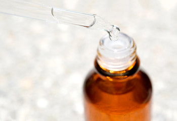 Dropping serum collagen moisturizer of face into clear yellow bottle soft light background. Protector skin Treatment facial essence oil, Vitamin C. Beauty and spa Concept.