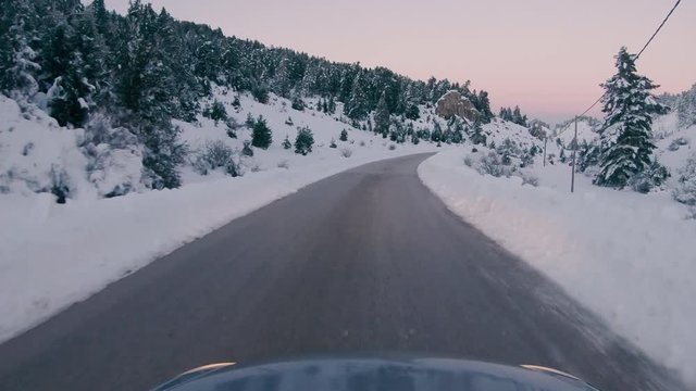 Driving on a snowy mountain road. Returning from Ziria ski center. Sunset colors in the horizon.