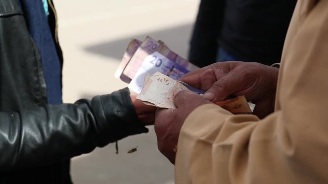 Local Moroccan man holding money in his hand, paying for a Safari in Cash.