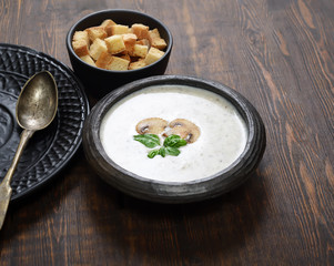 Champignon mushroom cream soup in bowl on wooden background. Rustic style. 