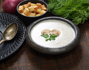 Champignon mushroom cream soup in bowl on wooden background. Rustic style. 