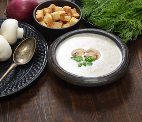 Champignon mushroom cream soup in bowl on wooden background. Rustic style. 