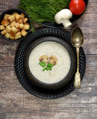 Champignon mushroom cream soup in bowl on wooden background. Rustic style. Top view.