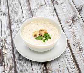 Champignon mushroom cream soup in bowl on wooden background. Rustic style. 