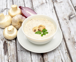 Champignon mushroom cream soup in bowl on wooden background. Rustic style. 