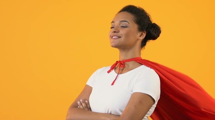 Self-confident afro-american woman with crossed hands in red cape, super hero