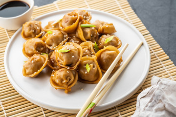 Home made chinese and korean dumplings served on the traditional steamer and bamboo mat decorated with soy sauce, parsley, giner.