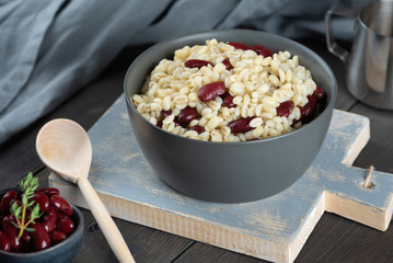 Pearl barley porridge in a plate on a black wooden background