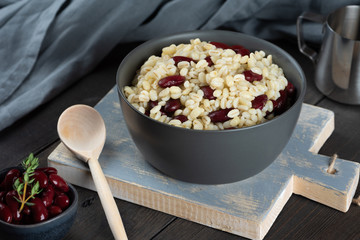 Pearl barley porridge in a plate on a black wooden background