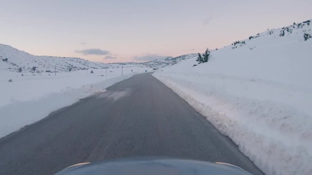 Driving on a snowy mountain road. Returning from Ziria ski center. Sunset colors in the horizon.