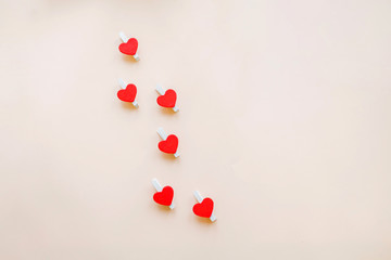 Red hearts on clothespins for attaching a sticker that says I love you on beige background. Happy Valentine's Day and March 8th, International Women's Day Concept. COPY SPACE, Romantic greeting  CARD