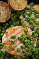 Closeup of fried hake medallions with green peas, selective focus, vertical shot